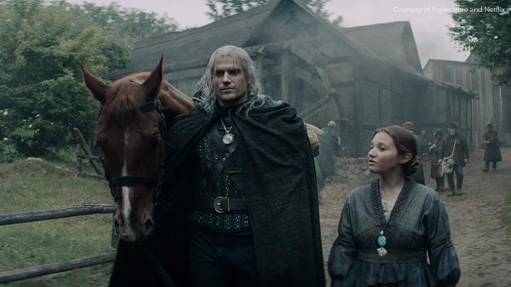 Henry Cavill as Geralt of Rivia walking with child